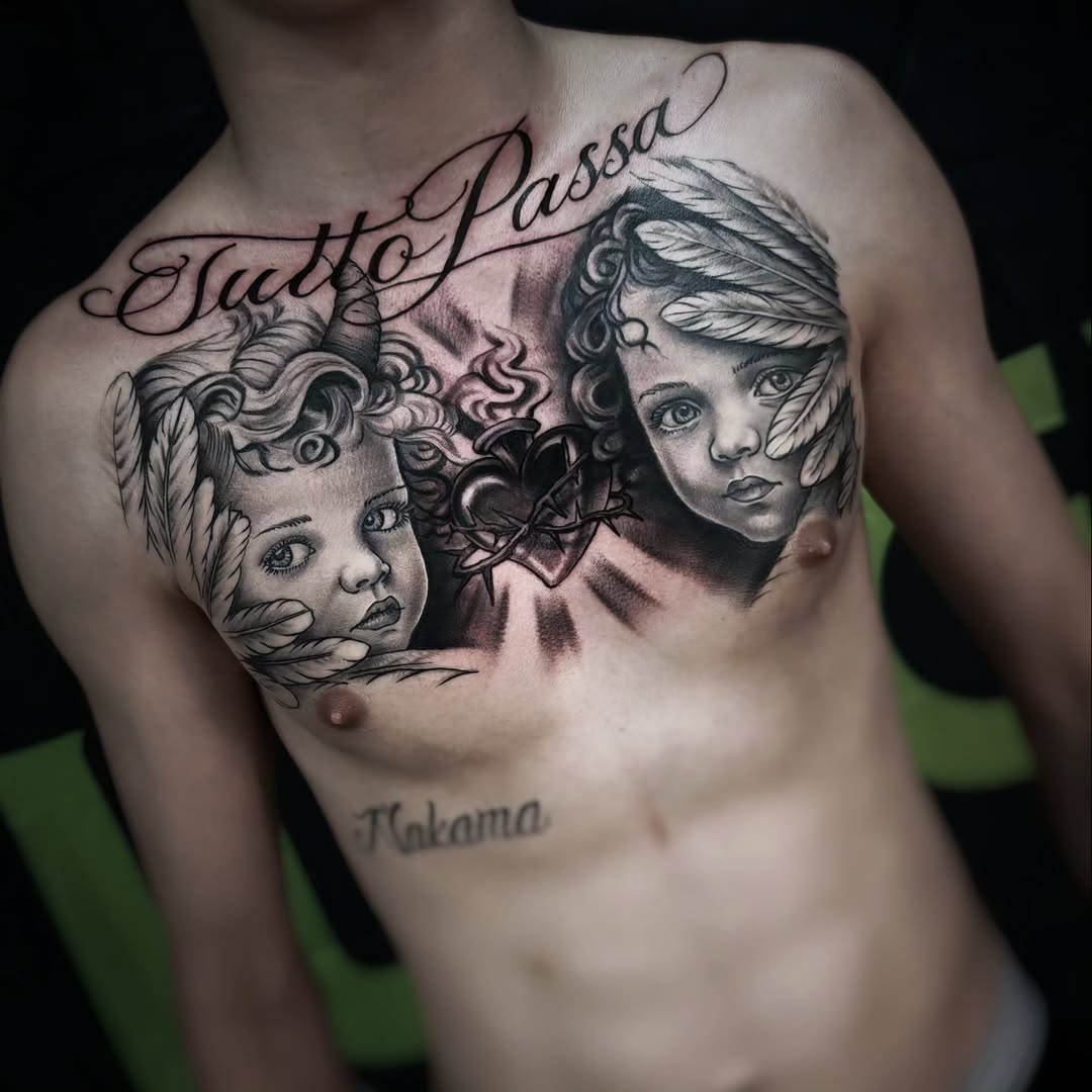 Chest tattoo featuring two child faces, one horned with feathers and one angelic with feathers, flanking a thorn-wrapped sacred heart, with cursive script above reading Tutto Passa.